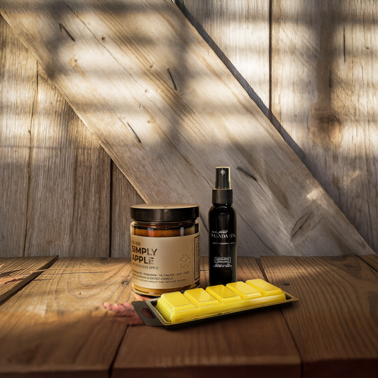 A scented candle from Candlogic, a 2 oz room spray and a yellow wax melt on a wooden surface with wooden wall background
