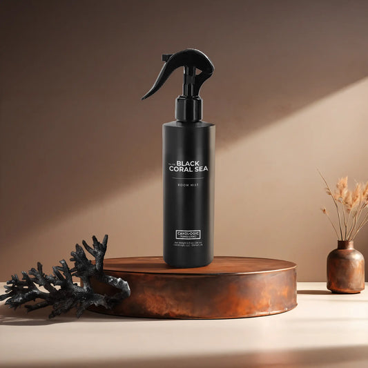 Candl•ogic’s 8 oz. room mist in a black spray bottle labeled ‘No. 035 Black Coral Sea’ on a copper tray with a piece of black coral and a copper vase in the background.