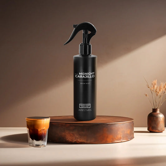Candl•ogic's 8 oz. room mist in a black plastic spray bottle labeled 'No. 044 Midnight Carajillo' on a copper tray with an espresso shot and a vase in the background.
