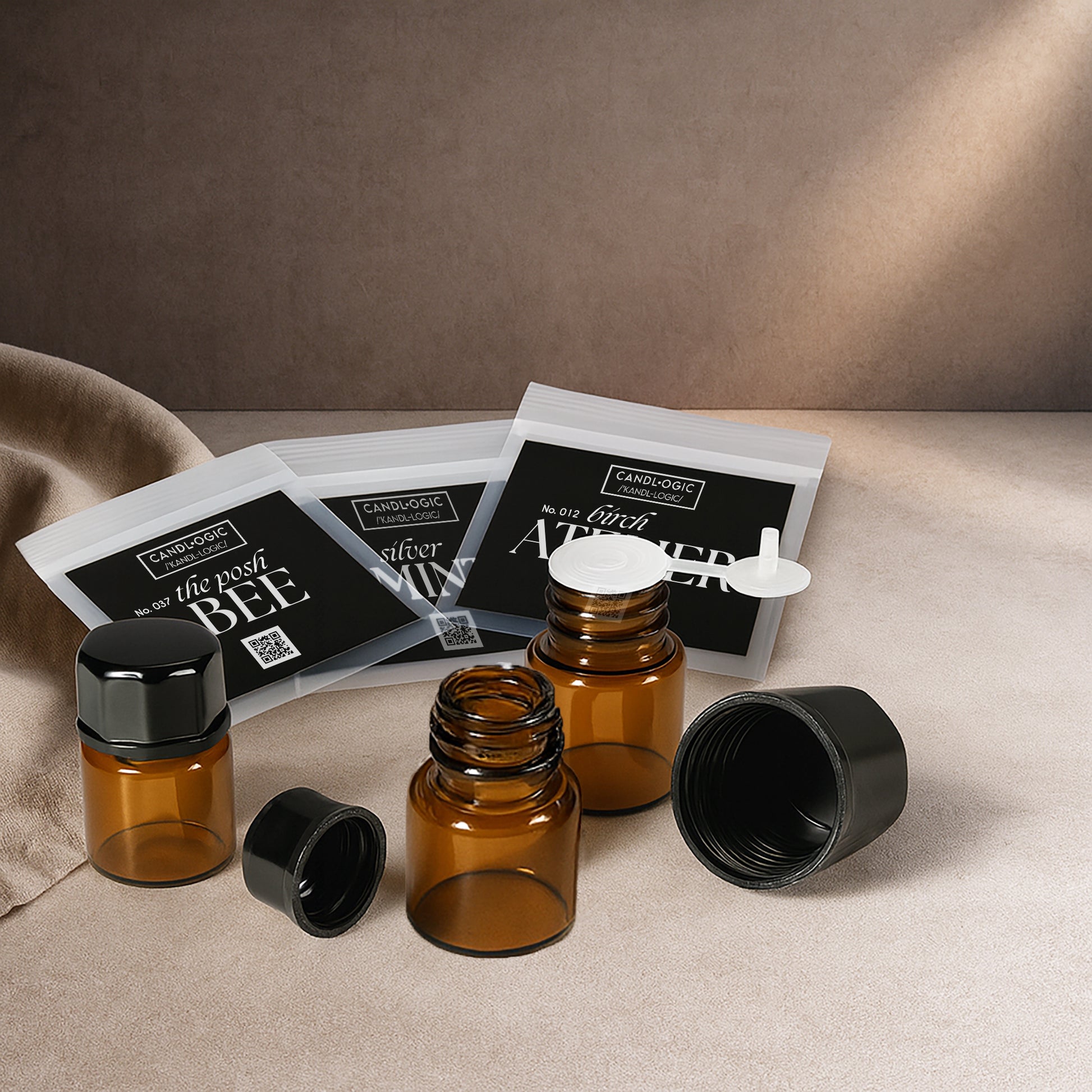 Amber glass bottles with black caps and resealable black-label pouches on a textured surface, minimalist luxury packaging for candles, essential oils, and home fragrance products.