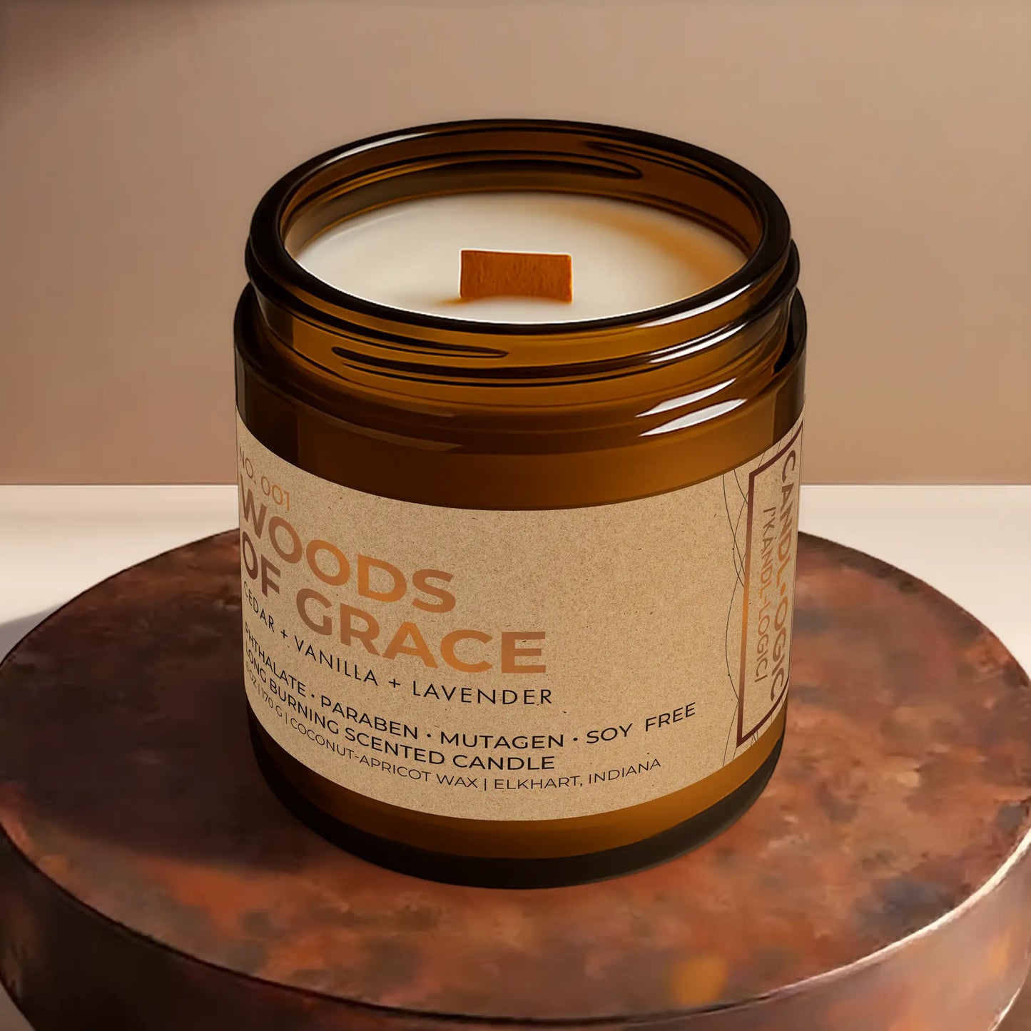 Candl•ogic’s scented candle with a wood wick viewed from the top in an amber glass 16 oz. jar labeled ‘No. 001 Woods of Grace’ on a copper tray.