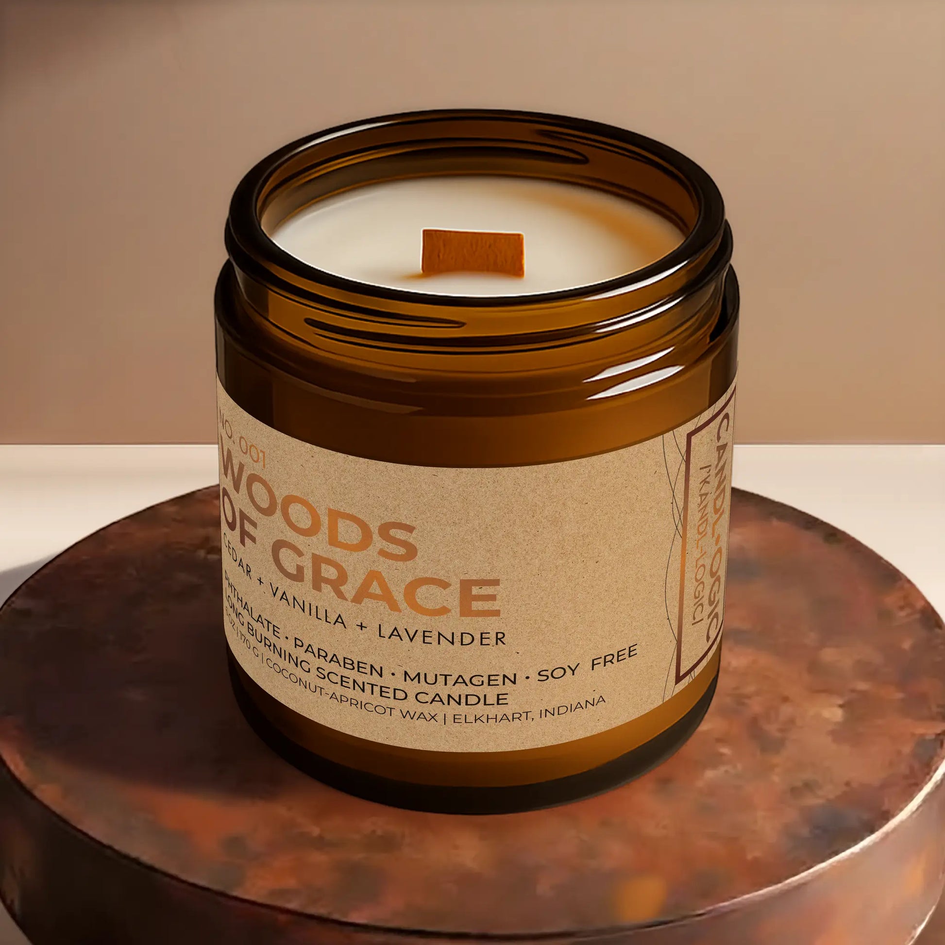 Candl•ogic’s scented candle with a wood wick viewed from the top in an amber glass 16 oz. jar labeled ‘No. 001 Woods of Grace’ on a copper tray.