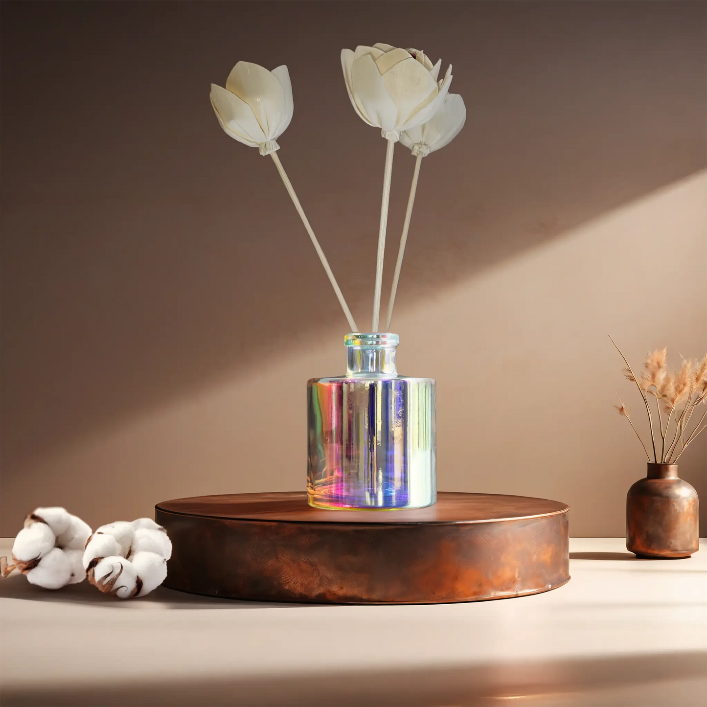 Candl•ogic’s reed diffuser set in an iridescent jar with rattan flower diffuser reeds for ‘No. 019 White Wash’ on a copper tray with cotton flower stems and a copper vase in the background.