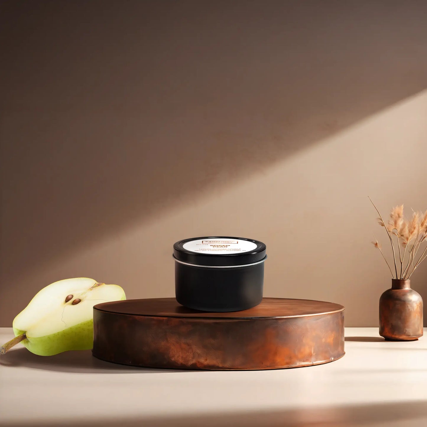Candl•ogic’s scented candle with a wood wick in a 3 oz. black metal tin labeled ‘No. 024 Spiced Pear’ on a copper tray with a sliced pear and a copper vase in the background.