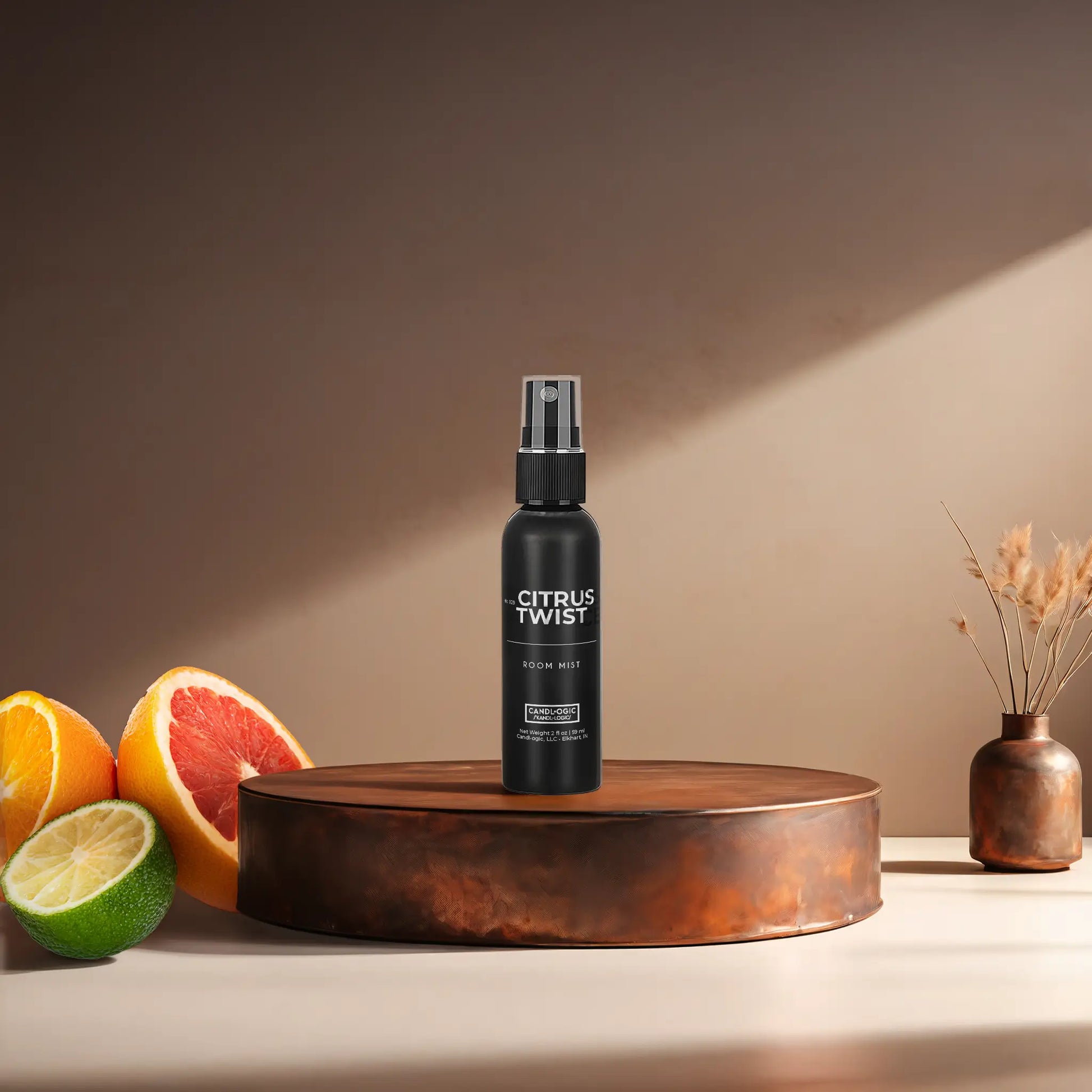 Candl•ogic’s 2 oz. room mist in a black spray bottle labeled ‘No. 029 Citrus Twist’ on a copper tray with citrus and a copper vase in the background.