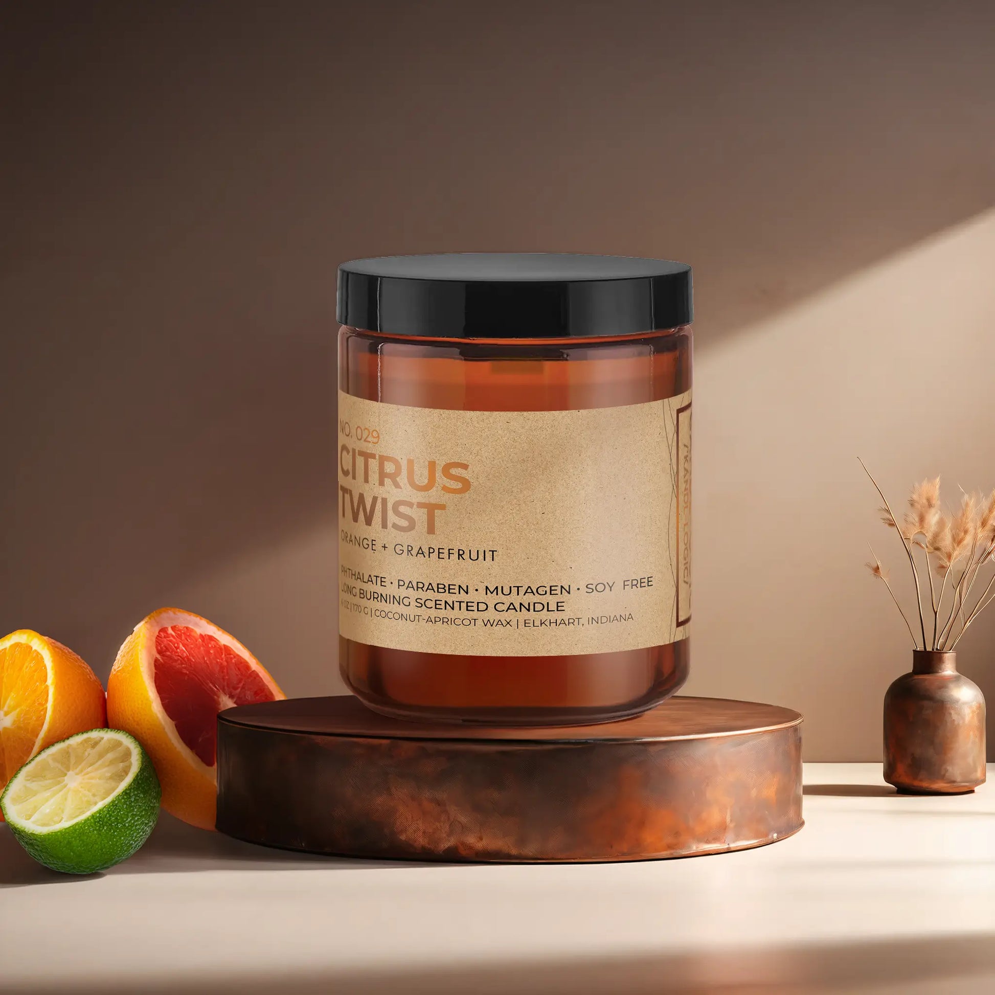 Candl•ogic’s scented candle with a wood wick in an amber glass 9 oz. jar labeled ‘No. 029 Citrus Twist’ on a copper tray with citrus and a copper vase in the background.
