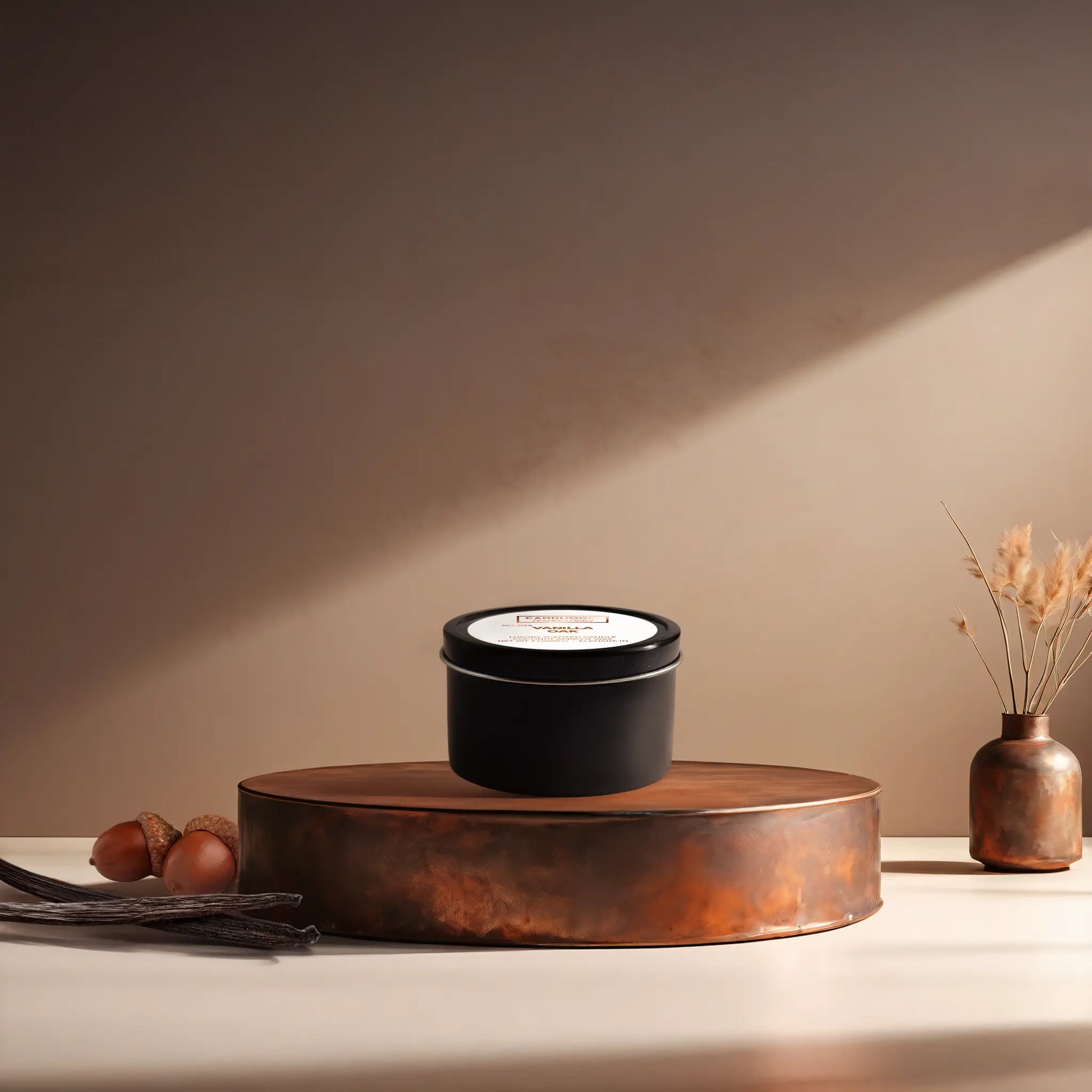 Candl•ogic’s scented candle with a wood wick in a 3 oz. black metal tin labeled ‘No. 034 Vanilla Oak’ on a copper tray with acorns and vanilla beans and a copper vase in the background.