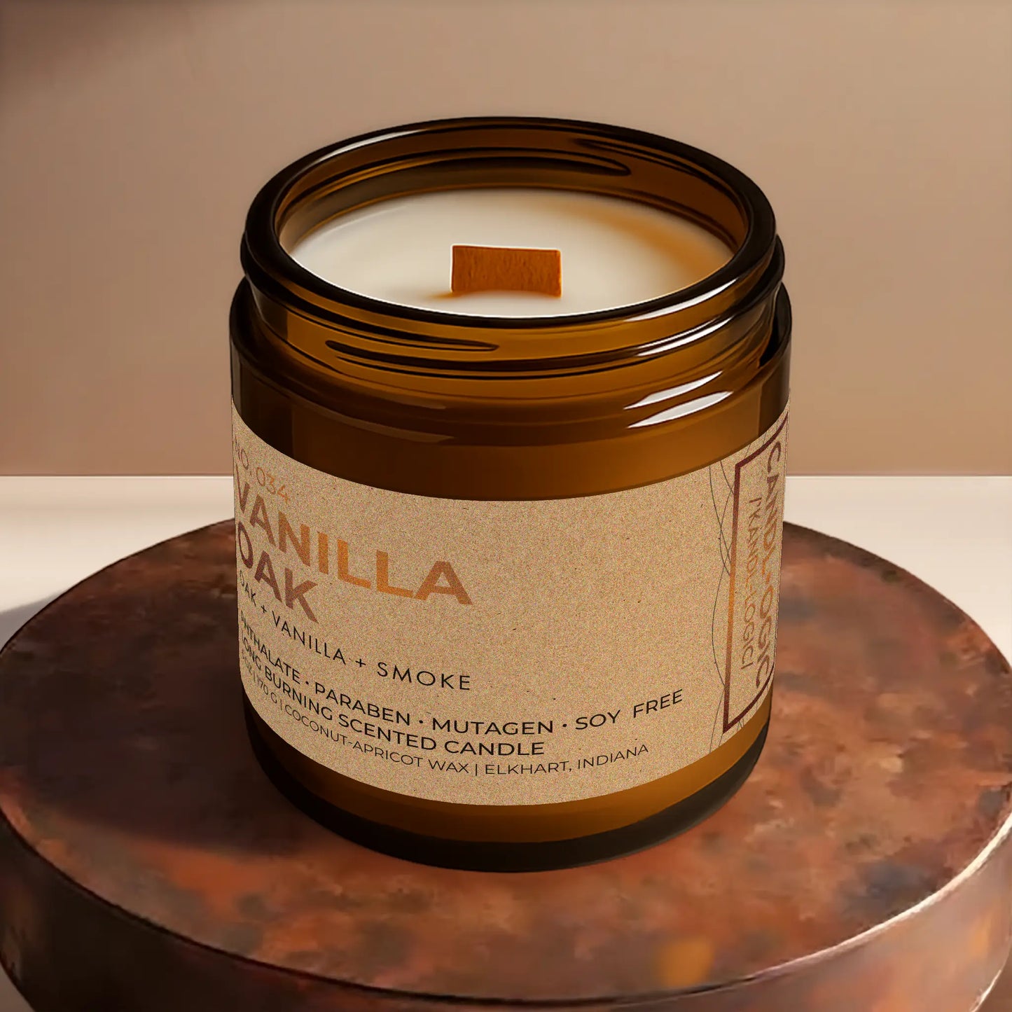 Candl•ogic’s scented candle with a wood wick viewed from the top in an amber glass 16 oz. jar labeled ‘No. 034 Vanilla Oak’ on a copper tray.