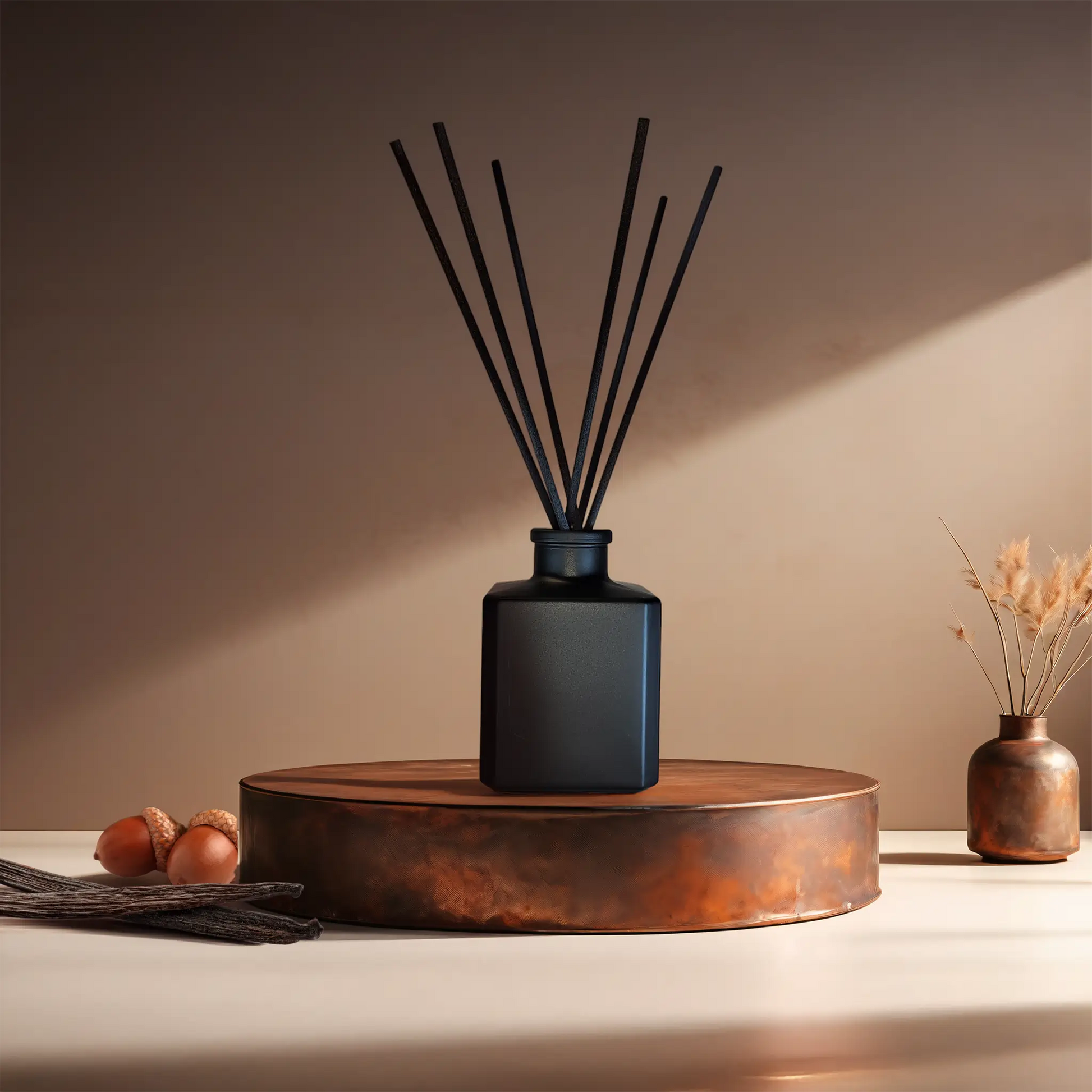 Candl•ogic’s reed diffuser set in small black glass cube with black fiber diffuser reeds for ‘No. 034 Vanilla Oak’ on a copper tray with acorns and vanilla beans and a copper vase in the background.
