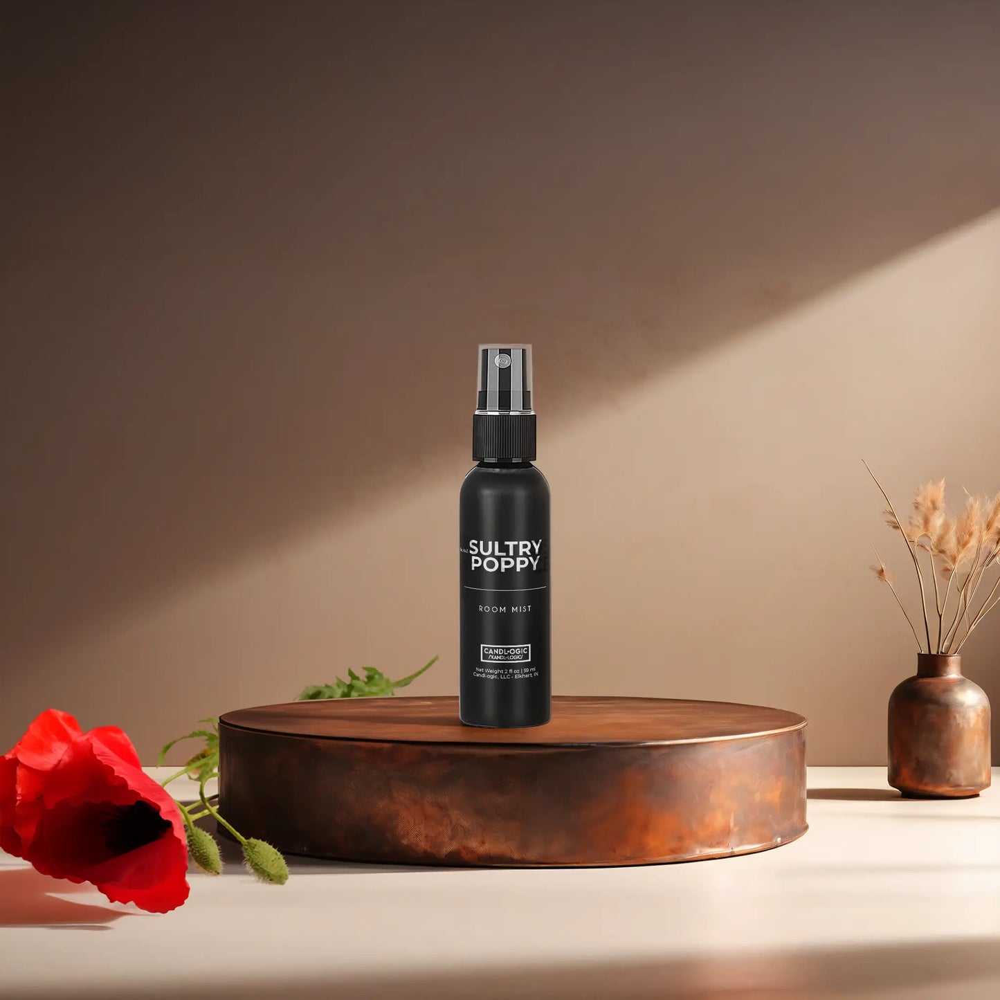Candl•ogic's 2 oz. room mist in a black spray bottle labeled 'No. 043 Sultry Poppy' on a copper tray with a red poppy flower and a vase in the background.